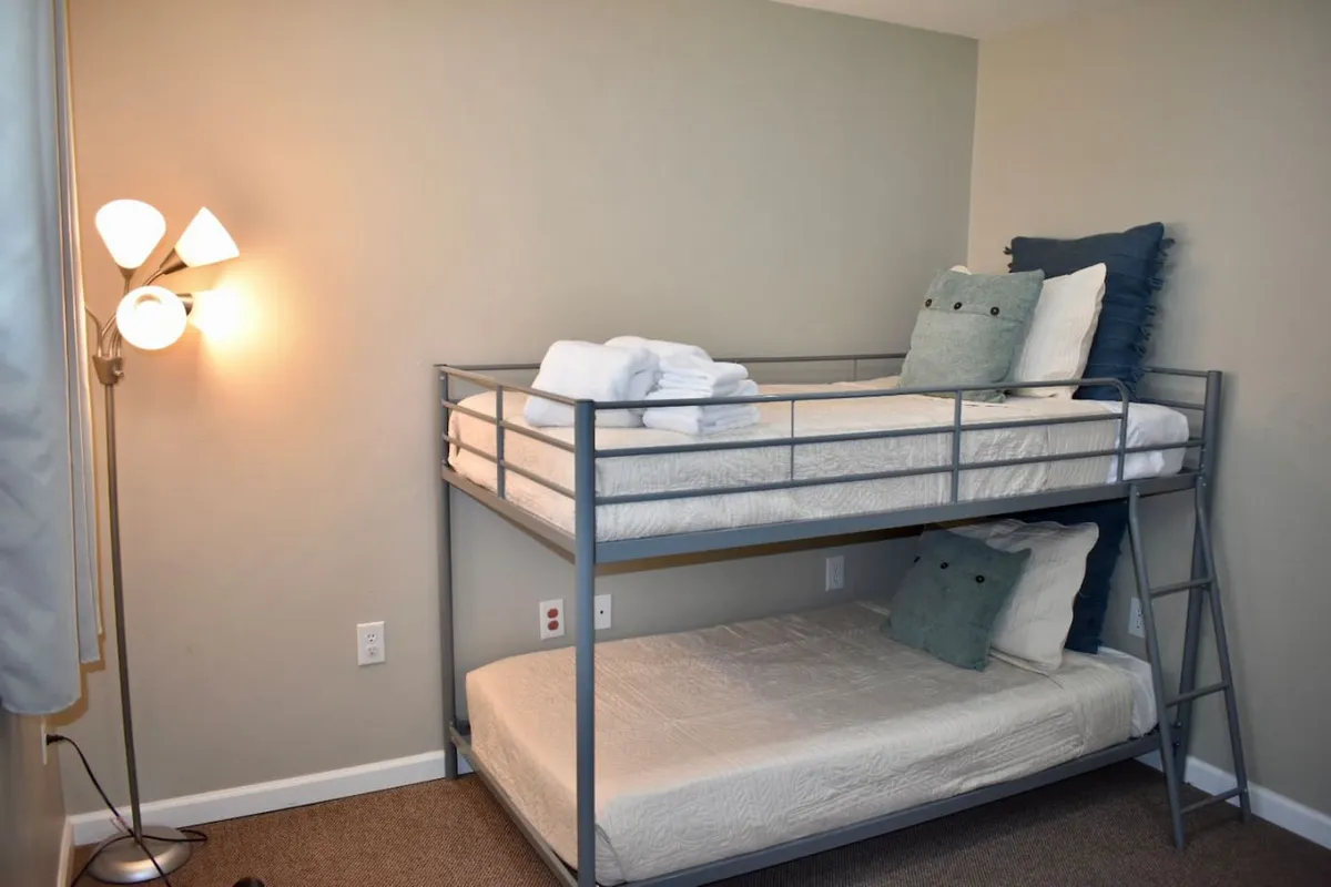 A comfortable bunk bedroom with a sturdy bunk bed, decorative pillows, and a lamp. The setup is playful yet cozy, making it an inviting space for children to unwind or share late-night conversations.