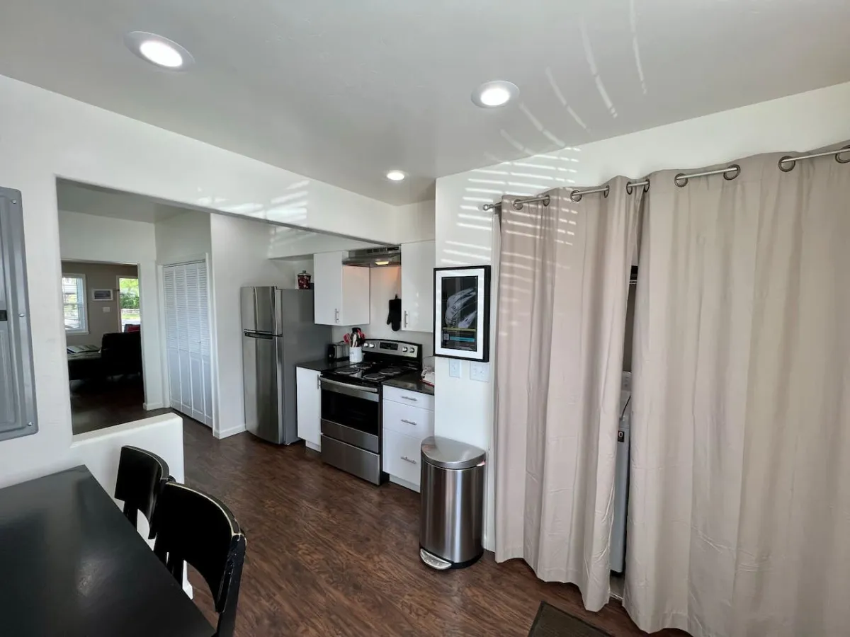 A cozy kitchen scene with kitchen appliances, ample counter space, and a splash of decorative artwork and curtains, creating an inviting atmosphere for cooking and socializing.